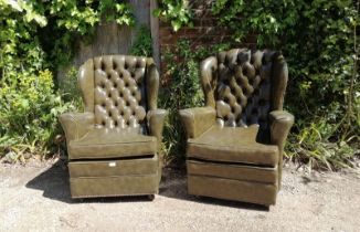 A pair of vintage Chesterfield style wingback armchairs, upholstered in faux green leather with