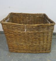 A large vintage woven willow log basket, with pierced handles to either side. H62cm W84cm D67cm (