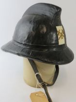 A 1970s Belgian Fire Service black cork fire helmet with brass badge.