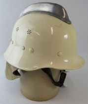 A 1980s Dutch Fire Service white steel fire helmet with polished metal comb and leather neck cowl.