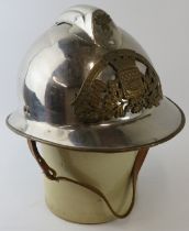 A 1980s French Paris Fire Service polished chrome fire helmet with brass mounts