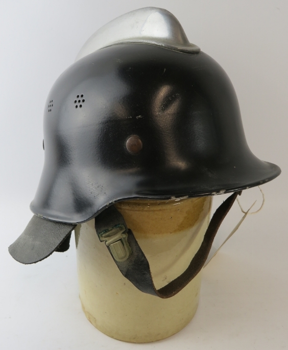 A 1960s German black steel fire helmet with alloy mounts and leather neck cowl