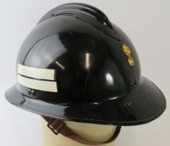 A 1970s Luxumberg Fire Service black steel fire helmet with brass badge.