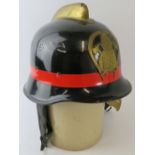 A 1970s Spanish Fire Service black steel fire helmet with brass comb and badge
