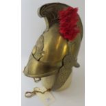 A late 19th century French brass fire helmet with chin strap, high comb and red feather hackle. *