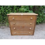 An antique light oak shaker style chest housing four long drawers with turned wooden knob handles.