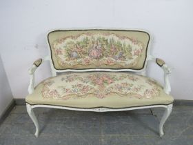 A vintage French two-seater sofa, painted white and distressed, upholstered in tapestry material