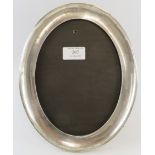 A 1920s oval silver mounted photo frame with mahogany and velvet easel back. 20cm x 25.5cm.