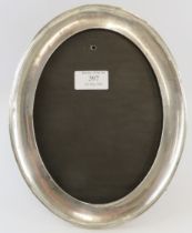 A 1920s oval silver mounted photo frame with mahogany and velvet easel back. 20cm x 25.5cm.