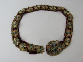 A Victorian gilt metal enamelled belt in the Art Nouveau style, mounted on a red velvet backing.