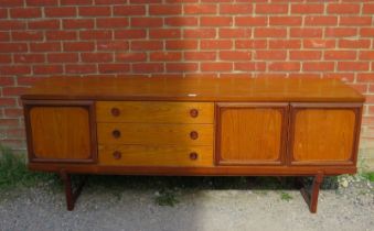 A mid-century teak sideboard, having three short drawers with turned wooden handles, flanked by