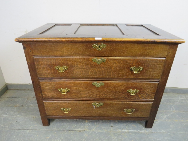 An antique oak chest in the 18th century taste, the panelled lid opening onto a shallow compartment,