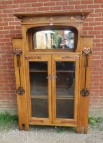 An Arts & Crafts light oak glazed cabinet in the manner of Glasgow school, the stepped cornice above