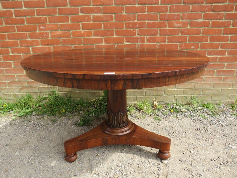 A 19th century rosewood tilt-top circular breakfast table, above a tapering plain pedestal with