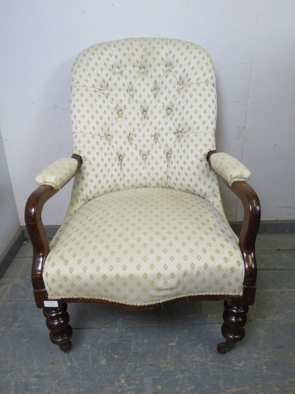 A Victorian mahogany open-sided button backed armchair, upholstered in patterned cream material,