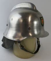 A 1980s Dutch Fire Service polished steel fire helmet with leather neck cowl.