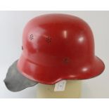 A 1960s German steel red fire helmet with leather neck cowl