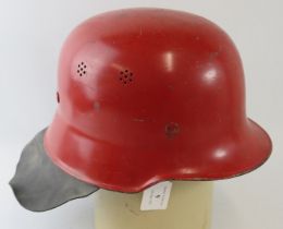 A 1960s German steel red fire helmet with leather neck cowl