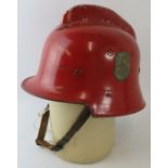 A 1950s West German red steel fire helmet with side mounted badge