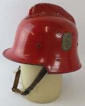 A 1950s West German red steel fire helmet with side mounted badge