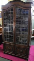 Oak bookcase with leaded glass doors over carved front two door cupboard