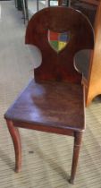 A 19th century mahogany hall chair with painted coat of arms to the back