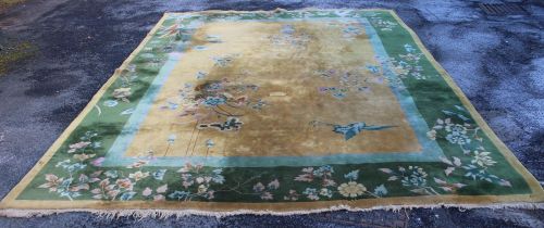 A roomsize Chinese carpet, golden ground with vase of l]flowers decoration. Green floral border