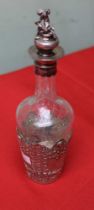 An embossed silver mounted glass liqueur decanter, the stopper with cast silver cherub top, silver h