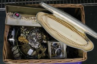 A small wicker hamper containing a large selection of costume jewellery