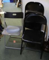 A pair of black folding metal chairs with another similar example