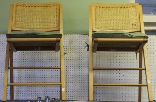 A pair of folding wooden chairs with rattan backs and seat pads including Fleur green seat cushions
