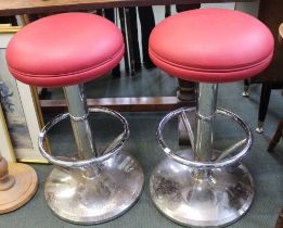 A pair of red leather topped chrome base bar stools