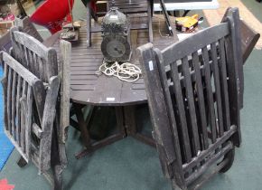 A wooden garden table with four folding chairs plus two folding steamer chairs