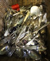 A wicker basket containing a wide selection of plated flatware, cutlery, etc