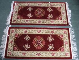 A pair of Chinese carved rugs, deep red ground with stylised motifs, bordered and fringed, 62cm x 12