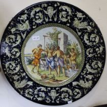 A Continental Majolica wall charger, classical scene to the centre, shepherd in discussion, bordered
