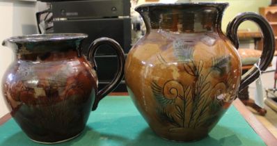 Two brown glazed mid 20th century terracotta pitchers decorated with flowers to the body