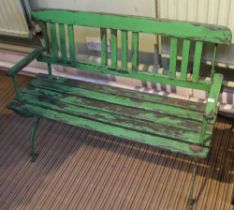 An Edwardian child's garden bench, wrought iron and wooden lathe of open arm design, green painted,