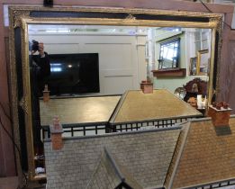 A large bevelled wall mirror in fancy gilt and black frame