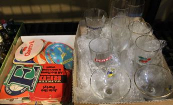 Various branded drinking glasses with a collection of beer mats