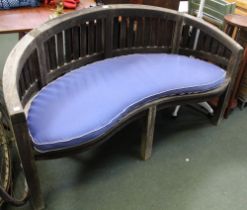 A crescent shaped well weathered garden bench