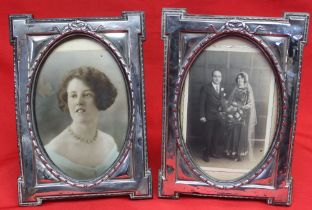 A pair of silver mounted photograph frames, embossed ribbon decoration, the image shown in an oval,