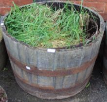 A metal banded half barrel garden planter with contents