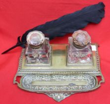 A late Victorian brass standish, with two glass inkwells and pen tray, complete with a black quill