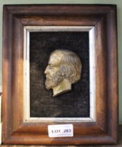 A small brass plaque of a head of a gentleman, framed