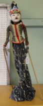 A carved and painted wood Indonesian puppet, fabric dressed, with stand base 57cm high