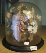 An early 20th century glass dome on stand containing a floral decoration