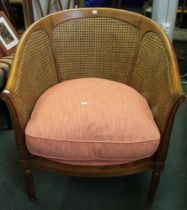A modern hardwood bergere tub chair with pink seat pad and cushion