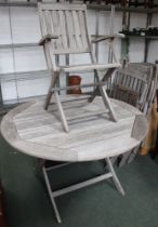 A well weathered teak garden table and four folding chairs