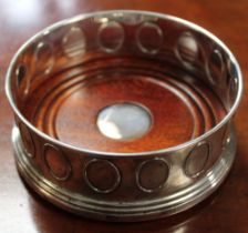 A silver Georgian design bottle coaster, having turned mahogany base, frieze of embossed ovals decor